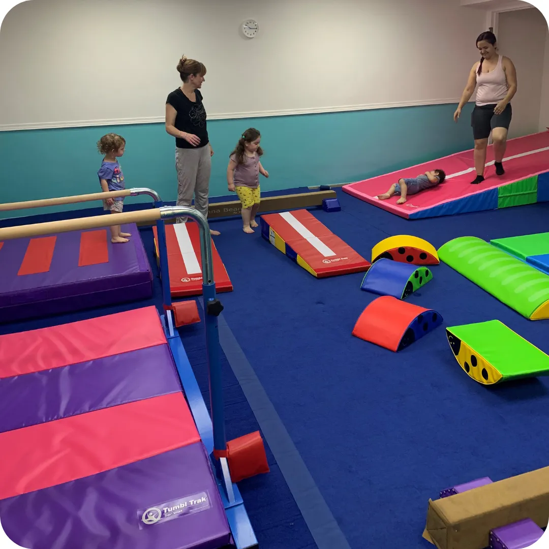 young kids and teachers playing on tumbling mats