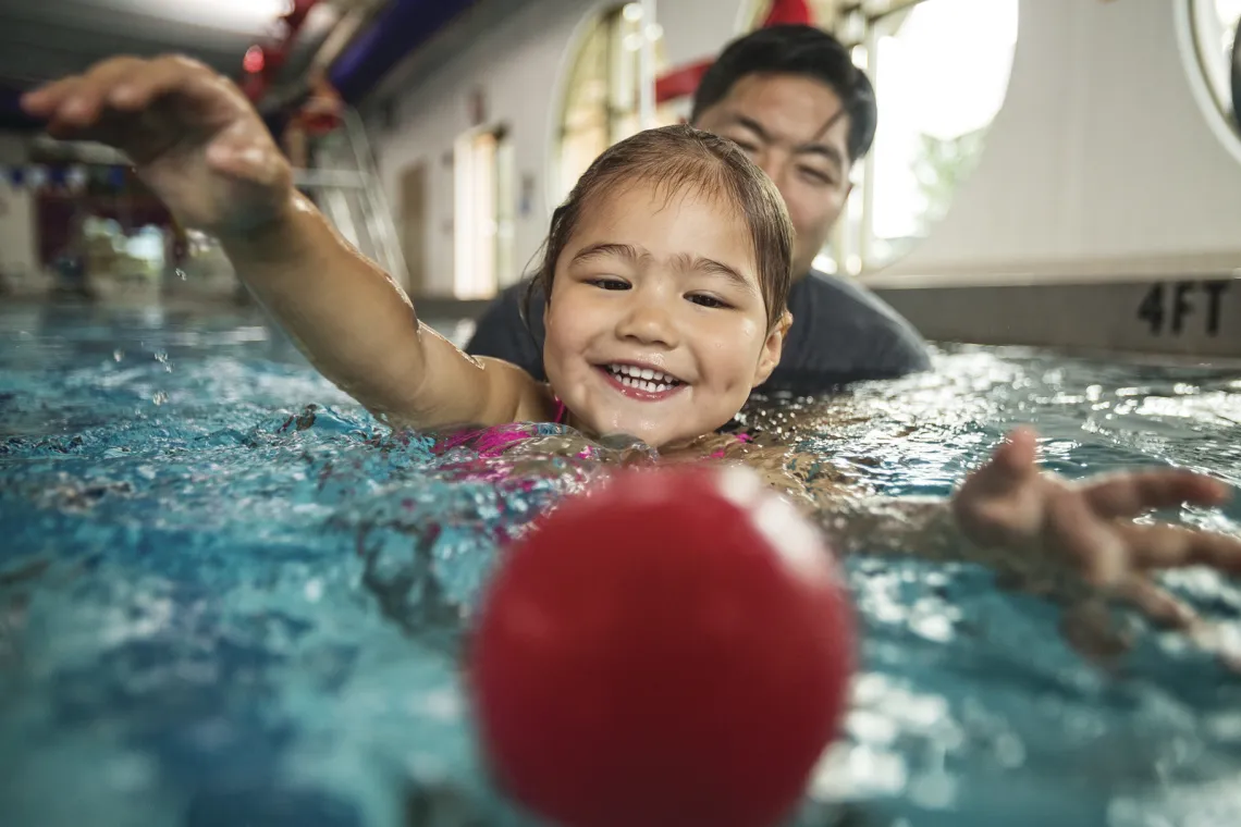 his photo shows a swim student swimming after red ball.